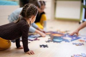 bambini collegamento sega puzzle pezzi nel un' bambini camera su pavimento a casa. divertimento famiglia attività tempo libero. foto