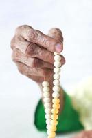 stretta di mano della donna senior pregando con perline