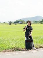 donna con bagaglio autostop lungo un' strada foto