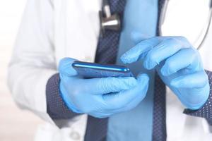 mano del medico in guanti protettivi utilizzando uno smartphone