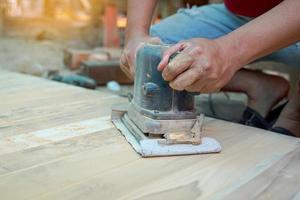 falegnami uso un' levigatrice per sabbia il superficie di il legna per liscio il carpenteria prima la pittura. morbido e selettivo messa a fuoco. foto