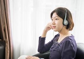 giovane asiatico donna corto capelli ascoltando musica nel vivente camera foto