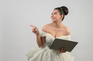 giovane asiatico bellissimo sposa posa con il computer portatile computer nel mano foto