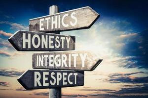 etica, onestà, integrità, rispetto - di legno cartello stradale con quattro frecce, tramonto cielo nel sfondo foto