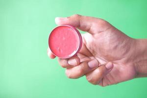 persona in possesso di lucidalabbra gelatina rosa su sfondo verde foto