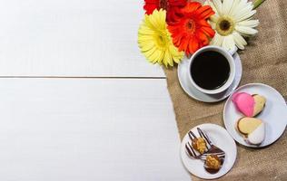 romantico fiori con caffè e dolce ossequi su il tavolo foto