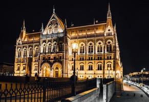 il parlamento ungherese di budapest sul danubio nelle luci notturne dei lampioni foto