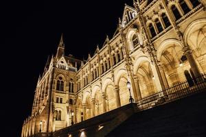 il parlamento ungherese di budapest sul danubio nelle luci notturne dei lampioni foto