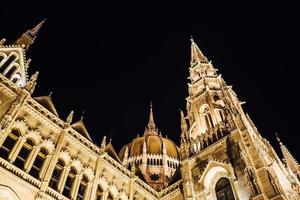 il parlamento ungherese di budapest sul danubio nelle luci notturne dei lampioni foto