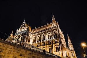 il parlamento ungherese di budapest sul danubio nelle luci notturne dei lampioni foto