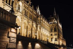 il parlamento ungherese di budapest sul danubio nelle luci notturne dei lampioni foto