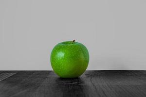 mela verde fresca su un tavolo in legno nero e sfondo bianco foto