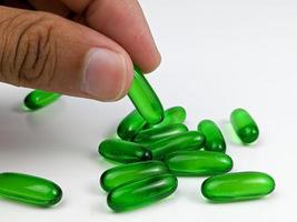 dito Tenere verde trasparente capsula pillole di vitamina e isolato su bianca sfondo foto