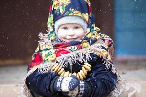 un' poco ragazza nel un' russo foulard con bagel a il maslenitsa vacanza. foto
