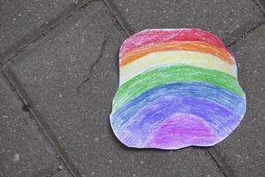 un' luminosa arcobaleno fatto di carta colorato con colorato matite bugie su il asfalto. foto