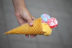 figli di mano detiene un' colorato ghiaccio crema cono su un' grigio sfondo. foto