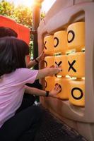 bambino ragazza giocando tic-tac-toe gioco a il terreno di gioco nel parco. foto