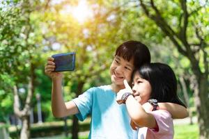 Due sorelle abbracciare mentre assunzione autoscatto con mobile smartphone nel il parco. contento amicizia famiglia concetto. foto