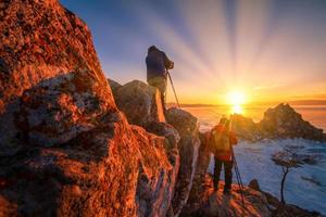 fotografo prendere foto di sciamanka roccia a tramonto con naturale rottura ghiaccio nel congelato acqua su lago baikal, Siberia, Russia.