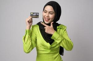 bellissimo musulmano donna con hijab Tenere credito carta al di sopra di bianca sfondo studio, shopping e finanza concetto. foto