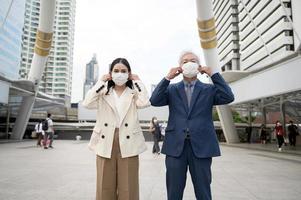 asiatico anziano maturo mezzo anziano uomo d'affari e giovane donna d'affari assunzione maschera via nel moderno città foto
