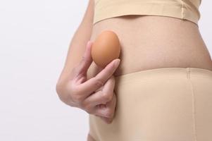 vicino su donna Tenere uova su pancia , preparare riproduttore fertilità , ovulazione stimolazione , maternità concetto foto