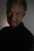buio lunatico ritratto di un più vecchio uomo nel Basso leggero indossare un' nero camicia foto