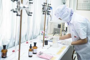 asiatico femmina specialista nel qualità controllo laboratorio l'esame pomodoro ingrediente cibo nel ricerca laboratorio, cibo industria foto