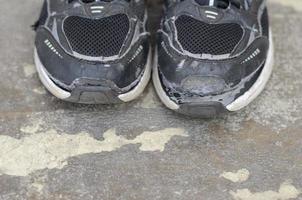 rotto vecchio nero scarpe da ginnastica su il pavimento copia spazio foto