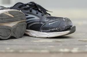 vecchio nero scarpe da ginnastica strappato dopo un' lungo tempo di uso. foto