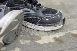 rotto vecchio nero scarpe da ginnastica su il pavimento foto