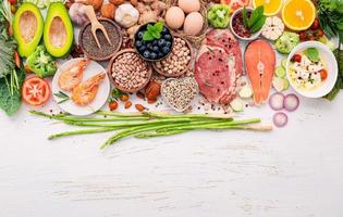 concetto di dieta chetogenica a basso contenuto di carboidrati. ingredienti per la selezione di cibi sani impostati su fondo di legno bianco. foto