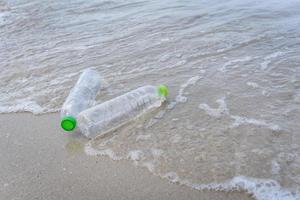 immondizia in mare con bottiglia di plastica sulla spiaggia sabbiosa mare sporco sull'isola - problema ambientale dell'inquinamento da rifiuti di plastica nell'oceano foto