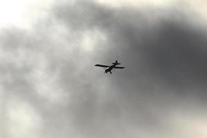 piccolo aereo volante nel il cielo contro buio nuvole foto