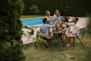 gruppo di giovane persone applauso con Cedro di il piscina nel il giardino foto