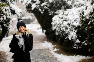 giovane donna nel caldo Abiti godendo nel neve con porta via caffè tazza foto