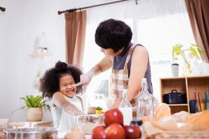 contento africano americano famiglia godere insieme mentre preparare il Farina per fabbricazione biscotti a casa foto