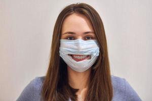 divertente sorridente ragazza con dentale bretelle indossare chirurgico maschera. foto