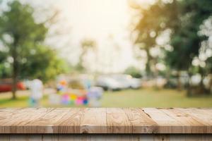 vuoto di legno tavolo superiore e astratto sfocato leggero bokeh e sfocatura sfondo di giardino alberi nel luce del sole. Prodotto Schermo modello con copia spazio. foto