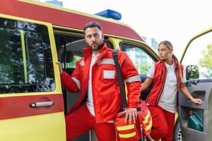 paramedico infermiera e emergenza medico a ambulanza con kit. un' paramedico, in piedi a il posteriore di un ambulanza, di il Aperto porte. foto