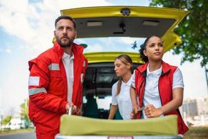 paramedici con un' barella vicino un ambulanza. paramedici nel uniforme assunzione barella su il ambulanza auto foto