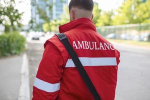 ambulanza personale membro a partire dal il indietro con il suo emergenza zaino , e vitale segni tenere sotto controllo. ambulanza scritto su il suo Indietro. foto