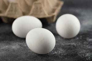 tre uova fresche di pollo crudo su uno sfondo di marmo foto