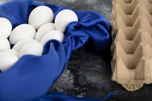 uova di gallina crude bianche con su una tovaglia blu