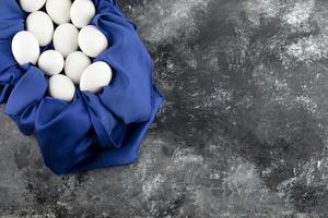 uova di gallina crude bianche con su una tovaglia blu