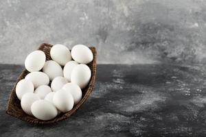 un vimini di legno pieno di uova di gallina crude bianche foto