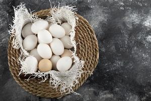 un cesto di legno pieno di uova di gallina crude bianche foto