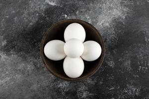 ciotola di legno piena di uova di gallina crude bianche foto