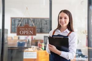 ritratto di un' donna, un' caffè negozio attività commerciale proprietario sorridente meravigliosamente e apertura un' caffè negozio quello è sua proprio attività commerciale, piccolo attività commerciale concetto. foto