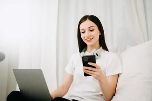 bellissimo donna ha svegliato su su un' bianca letto e Tenere caffè nel il mattina a casa nel mattina foto